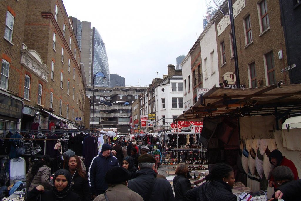 People shopping in stalls with a view of the city in Petticoat Lane market, Whitechapel, East London, 2010.