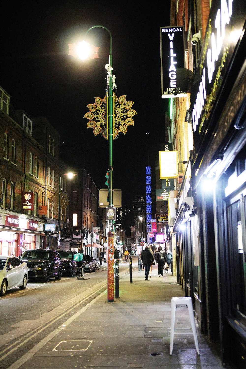 A street view of Brick Lane featuring a Banglatown decoration on a lamp post.