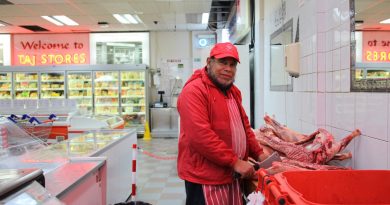 Taj Stores butcher at his work station, cutting up some meat, as he poses for the camera, Brick Lane, Whitechapel.