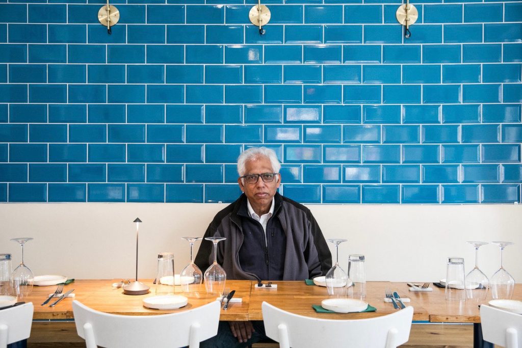 Owner Azmal Hussain posing from inside Preem restaurant, Brick Lane.