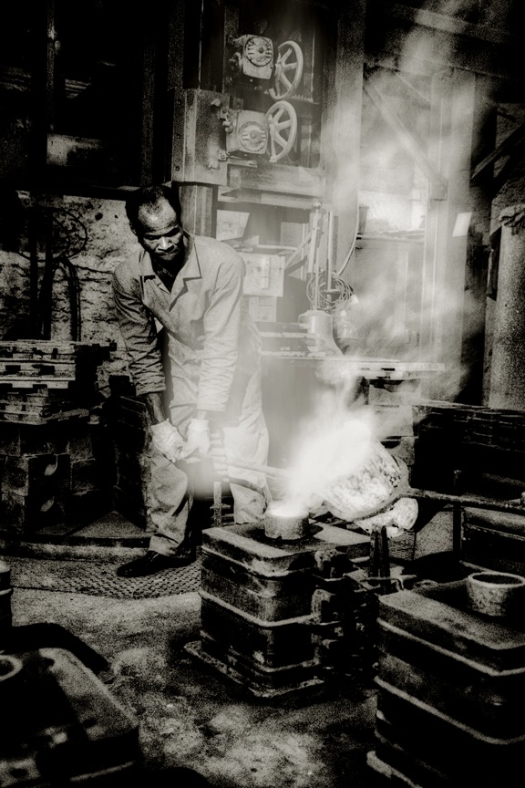 A worker pouring molten metal into a cast, Whitechapel Bell Foundry.