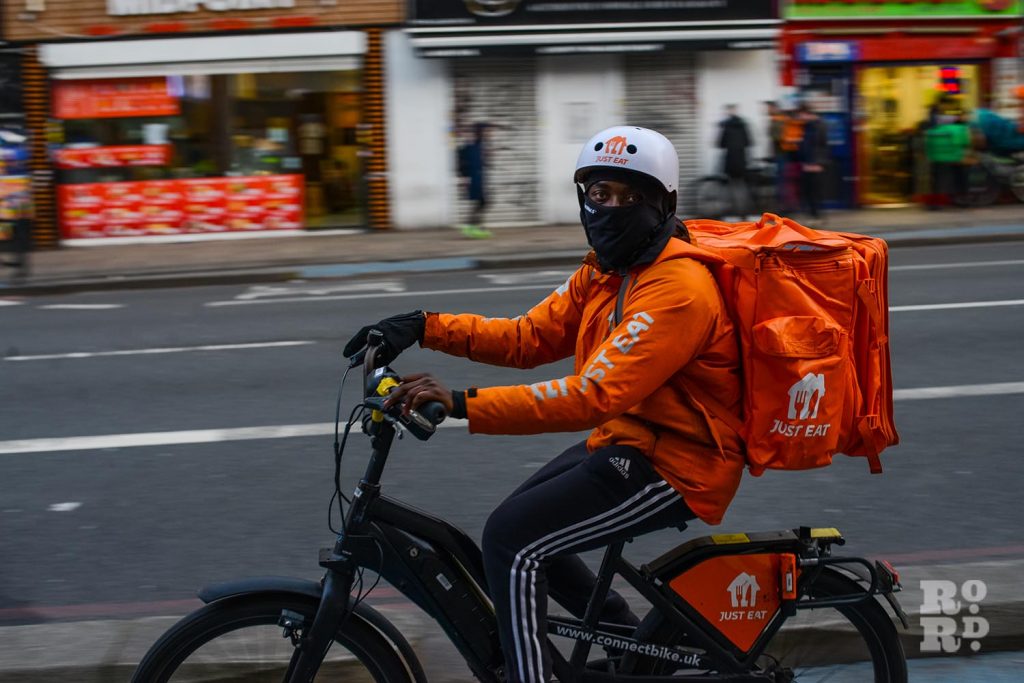 A Just Eat cycle courier cruising past in Whitechapel, East London, from a photo essay shot by photographer Matt Payne.