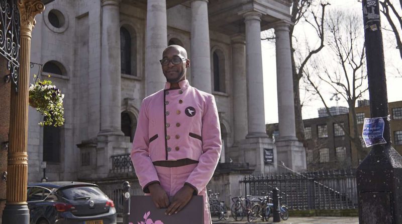 Ricardo, the cake concierge, stands in front of Christ Church, Spitalfields East London with a Hummingbird Bakery delivery before it reopens