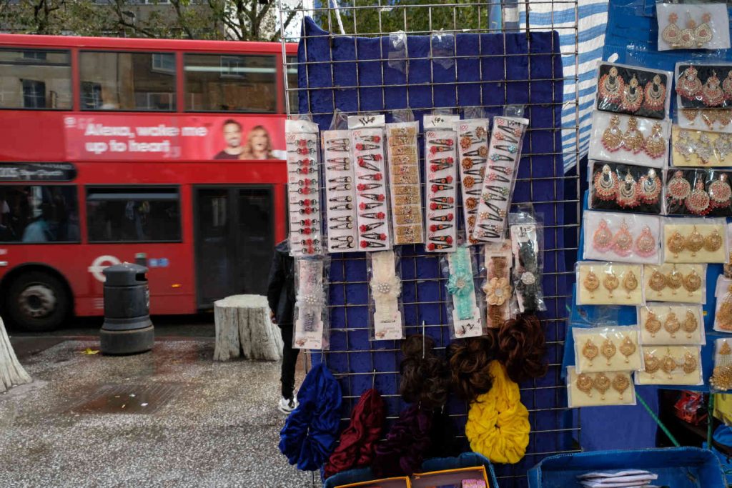 A stall selling earrings with a bus passing by in Whitechapel Market.