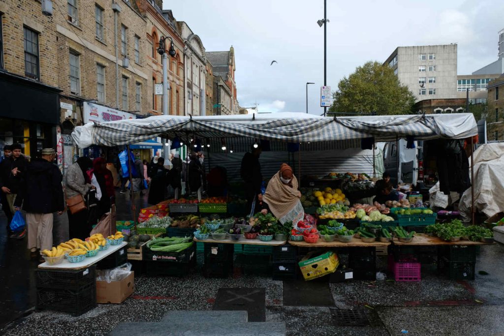 A woman browses at a fruit and veg stall in Whitechapel Market.