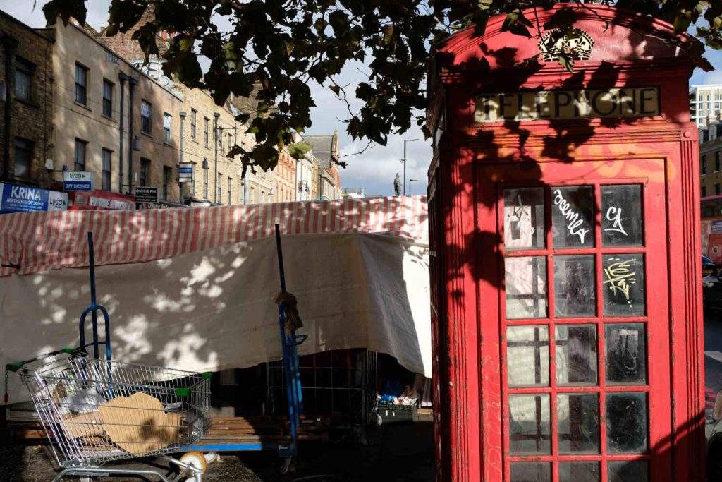 A phone booth and a shopping trolley in Whitechapel Market.