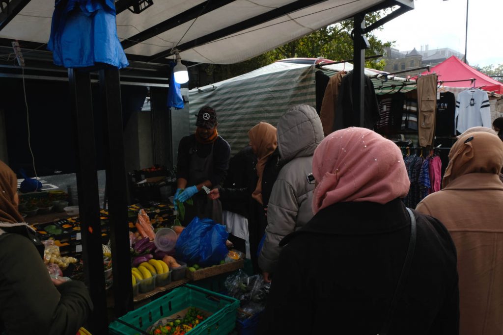 A woman buying fruit from a stall in Whitechapel market.