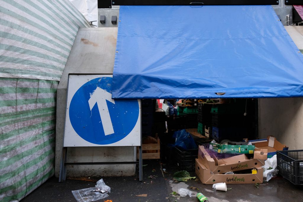A street sign leans against the back of a stall in Whitechapel market.