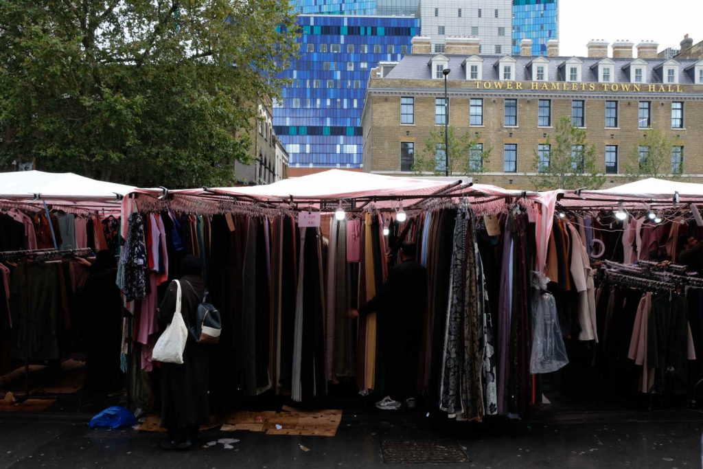 A stall in Whitechapel Market with Tower Hamlets Town Hall and the Royal London Hospital behind.