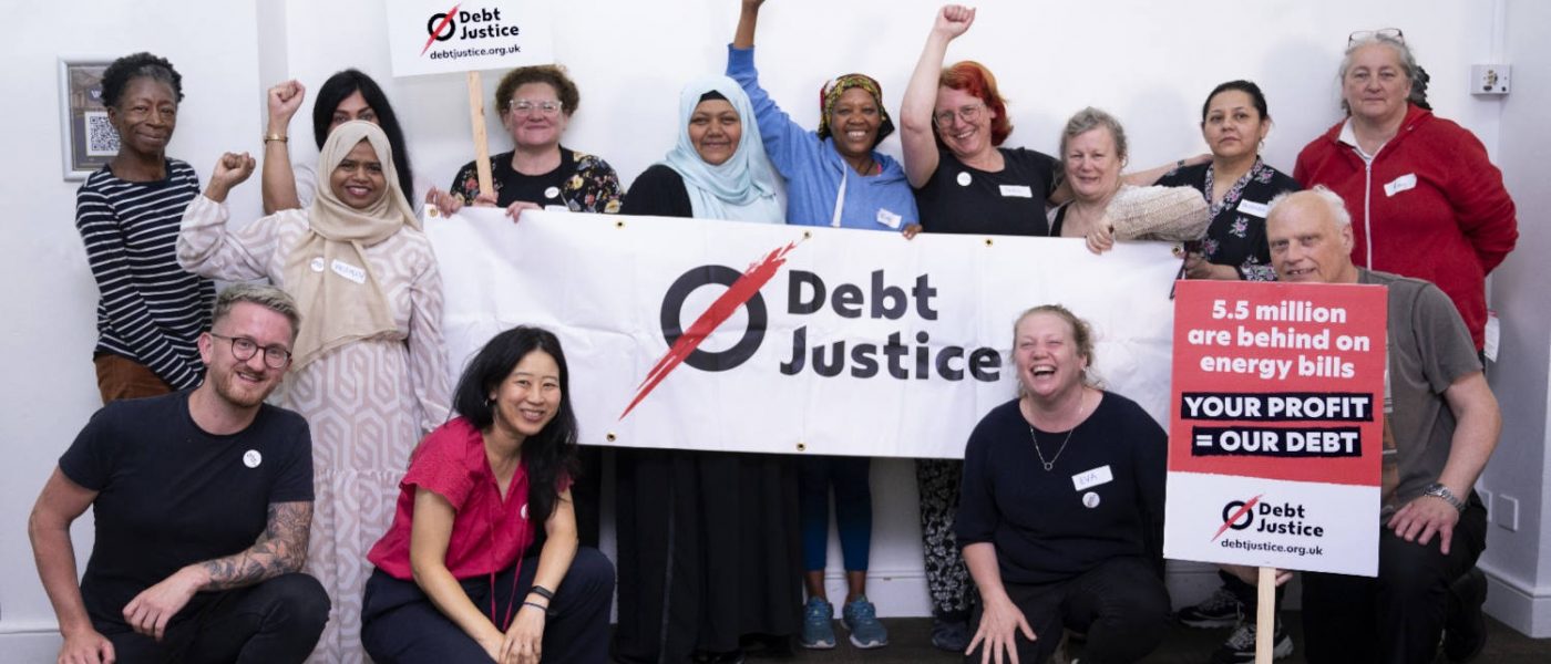 Members of Debt Justice posing with signs calling for more justice ways of dealing with household debt