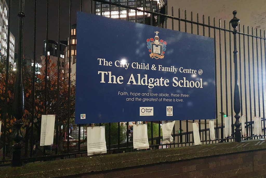 The Aldgate School sign outside the school. The sign reads 'The City Child & Family Centre @ The Aldgate School Faith, hope and love abide, these three: and the greatest of these is love.' followed by two logos of the Portal Trust and City of London.