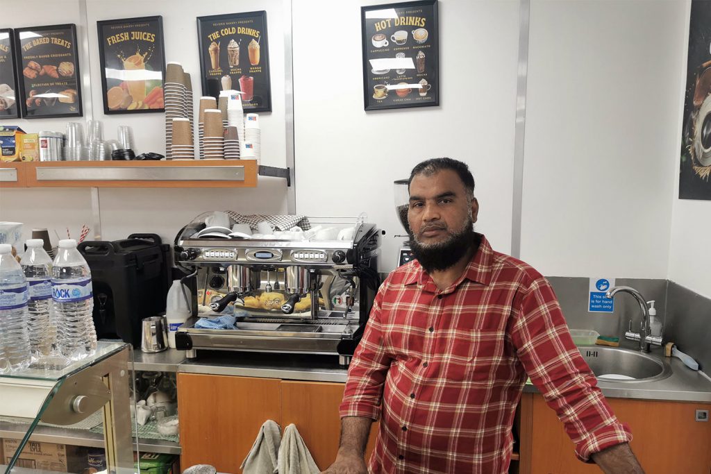 A man with a beard standing next to his coffee machine behind the counter of Reverie Bakery, Whitechapel 